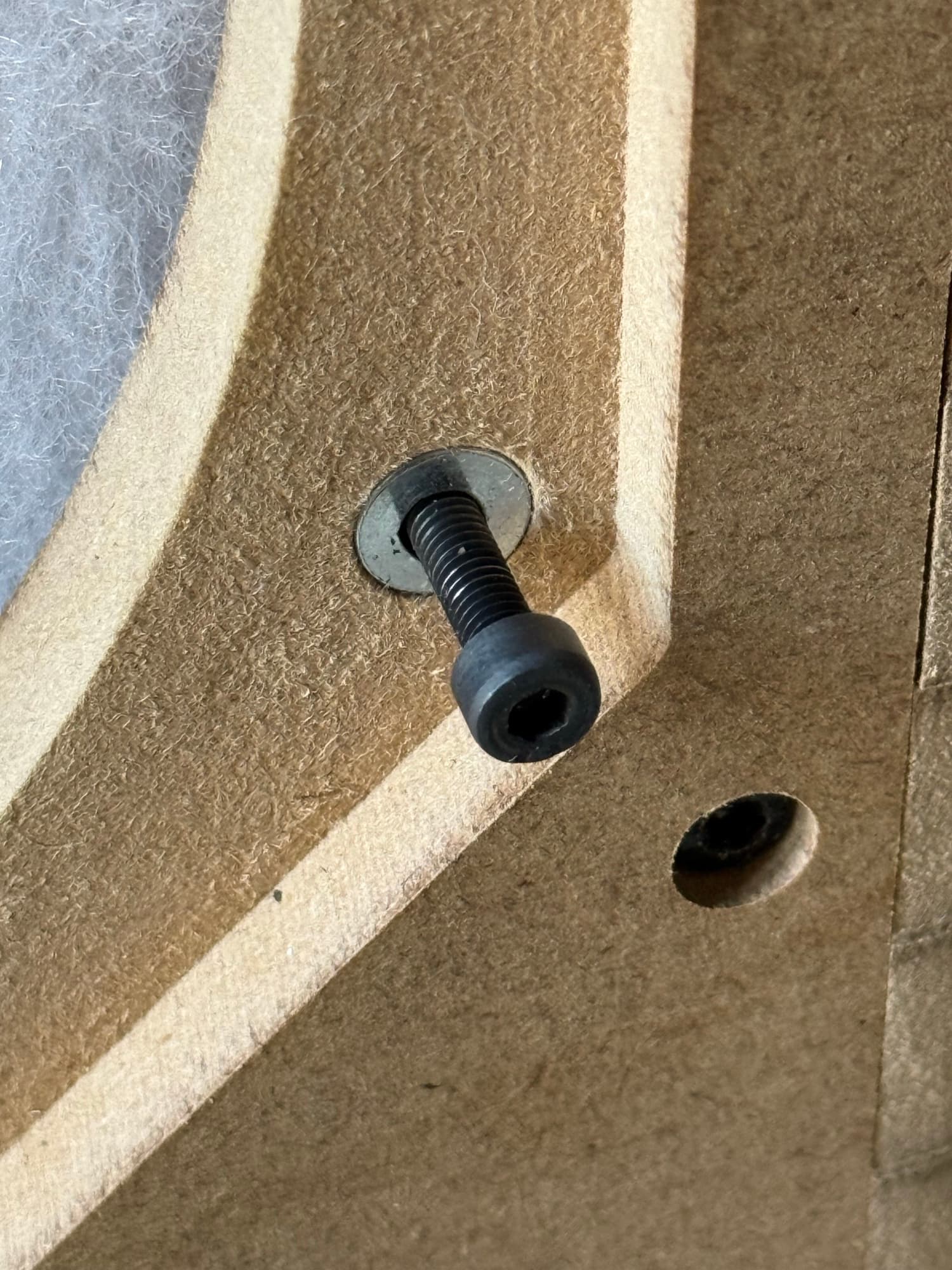 Tornillo Allen M4 roscado en la tuerca cilíndrica alojada en una capa de MDF del prototipo, junto al taladro de otra fijación.
