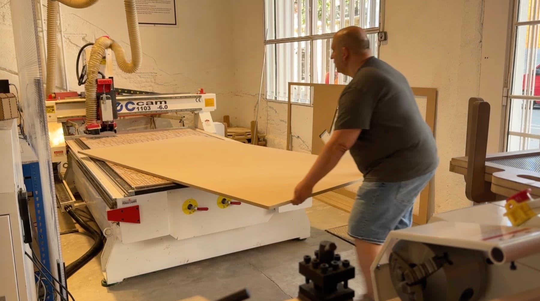 Un operario coloca un tablero de MDF sobre la mesa de una fresadora CNC